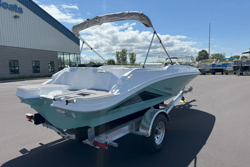 Slide: The Image of 2026 Hurricane SunDeck Sport 185 OB boat on trailer, parked outside a building. - 3