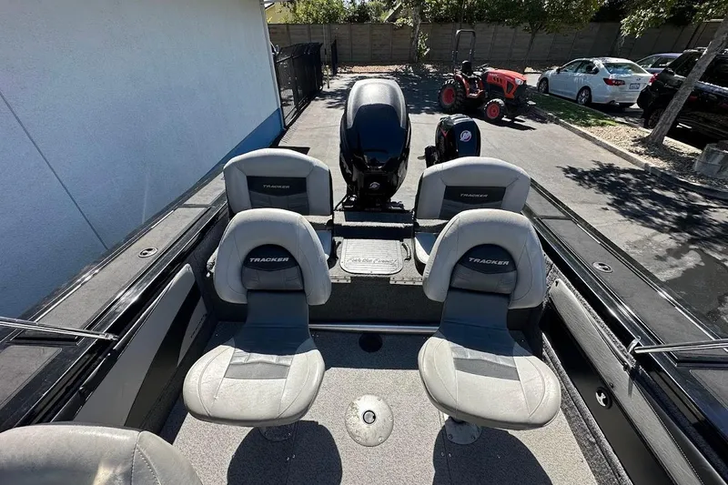 Slide: The Image of 2018 Tracker Targa V-19 Combo boat interior with seating and motor, parked outdoors. - 13