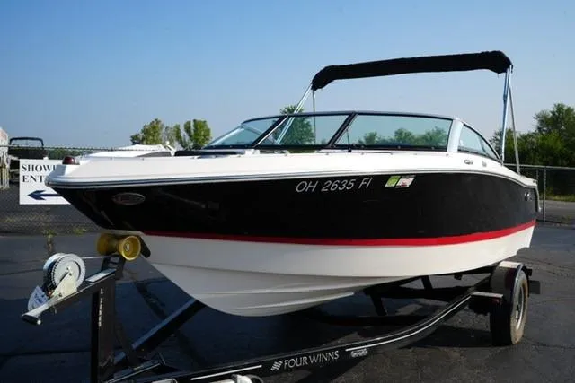 Slide: The Image of 2013 Four Winns H190 boat on trailer, black and white design, parked outdoors. - 1