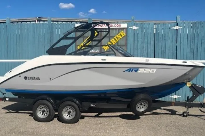 The Image of 2026 Yamaha Boats AR220 on trailer, parked outdoors against a blue fence. - 0