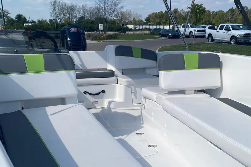 Slide: The Image of 2024 Tahoe T18 boat interior with white and green seating, parked outdoors. - 2