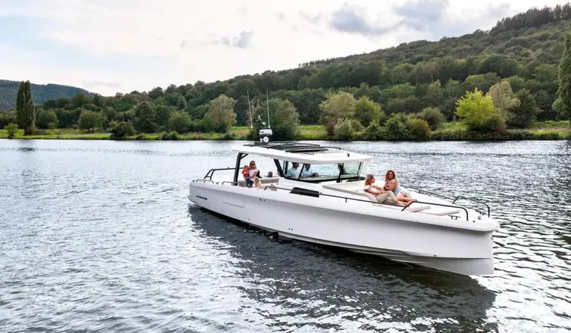 Slide: The Image of 2025 Axopar 45 Cross Top boat cruising on a scenic lake with passengers relaxing. - 3