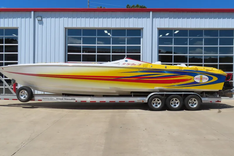 The Image of 2003 Cigarette 38 Top Gun speedboat on trailer, vibrant yellow with red and blue accents. - 0