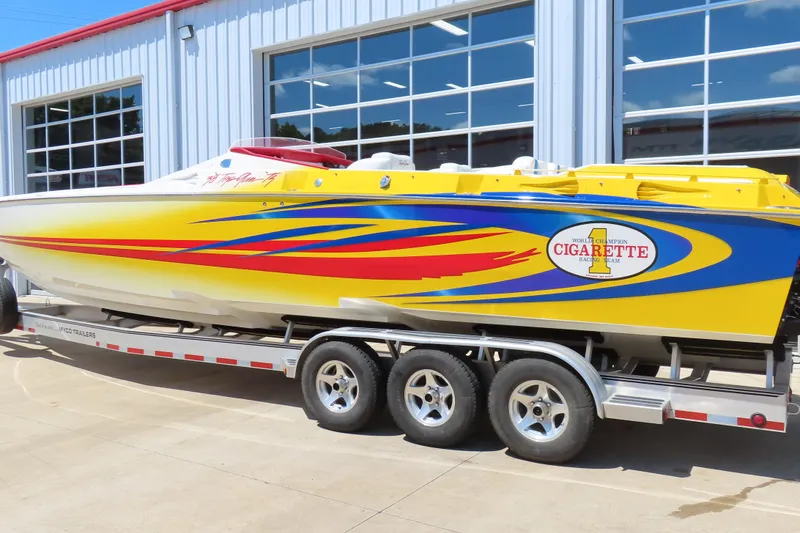 Slide: The Image of 2003 Cigarette 38 Top Gun speedboat with vibrant yellow and blue design on trailer. - 11