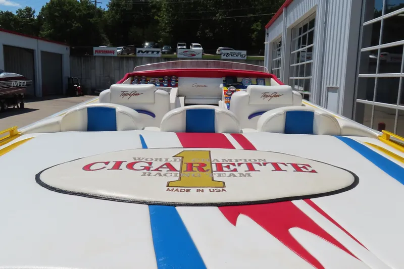 Slide: The Image of 2003 Cigarette 38 Top Gun boat with vibrant racing design and logo, parked outdoors. - 13