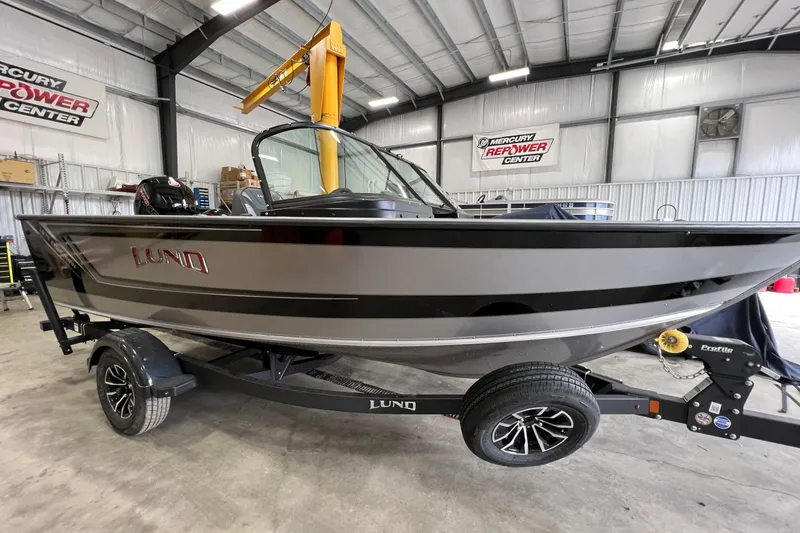 The Image of 2026 Lund 1875 Fisherman boat in showroom, sleek design, on trailer. - 1