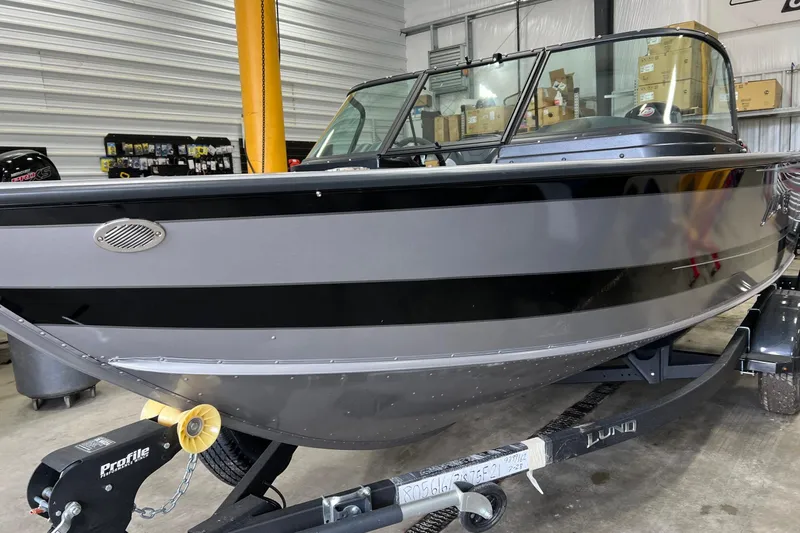 Slide: The Image of 2026 Lund 1875 Fisherman boat in showroom, sleek design, black and gray color scheme. - 10