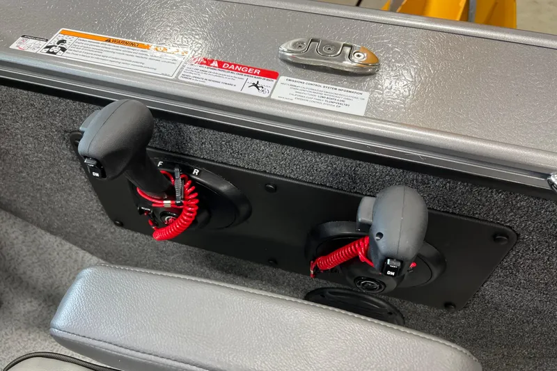 Slide: The Image of 2026 Lund 1875 Fisherman boat controls with safety warnings and red coiled cords. - 22