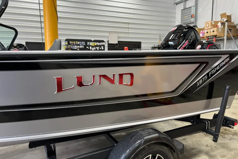 Slide: The Image of 2026 Lund 1875 Fisherman boat in showroom, featuring sleek design and branding. - 8