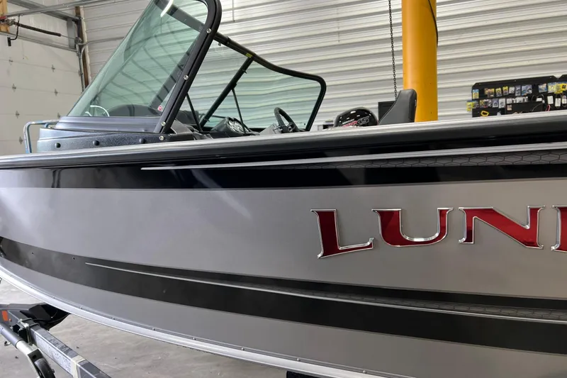 Slide: The Image of 2026 Lund 1875 Fisherman boat in garage, showcasing sleek design and windshield. - 9