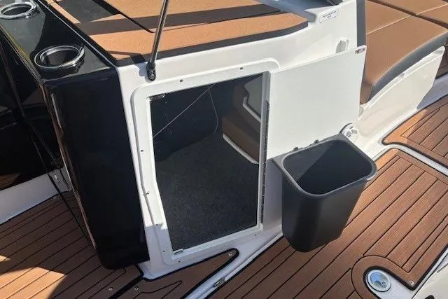 Slide: The Image of 2026 Yamaha Boats 222SE interior storage compartment with open door and trash bin on deck. - 14