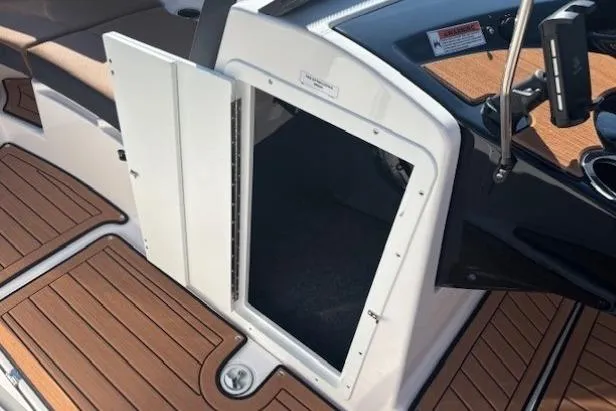 Slide: The Image of 2026 Yamaha Boats 222SE interior storage compartment with open hatch and wood-textured flooring. - 15