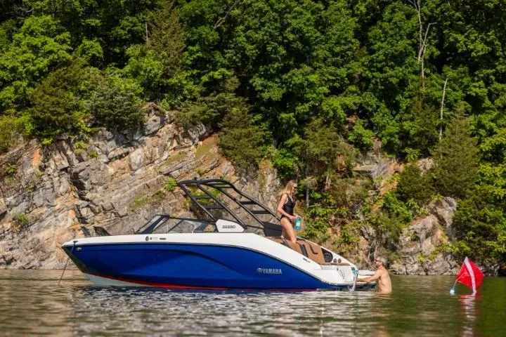 Slide: The Image of 2026 Yamaha Boats 222SE on a scenic lake with lush greenery and rocky cliffs. - 25