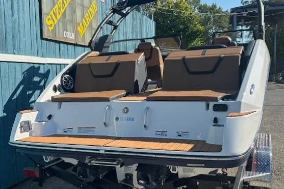 Slide: The Image of 2026 Yamaha Boats 222SE with brown seating, displayed outdoors at a marine dealership. - 3