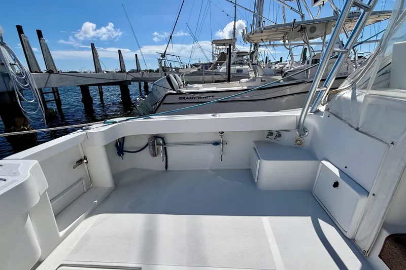 Slide: The Image of 2002 Luhrs 32 Open boat cockpit with marina view, featuring clean white deck and seating. - 14