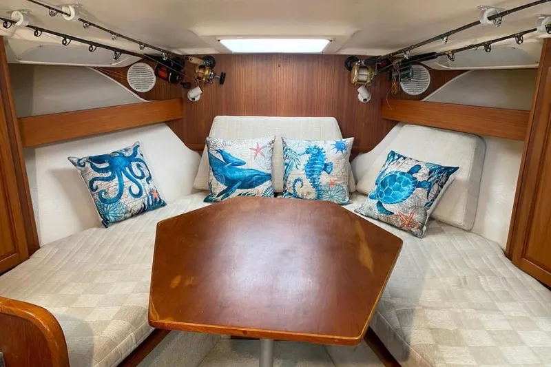 Slide: The Image of 2002 Luhrs 32 Open cabin interior with nautical-themed pillows and wooden table. - 44