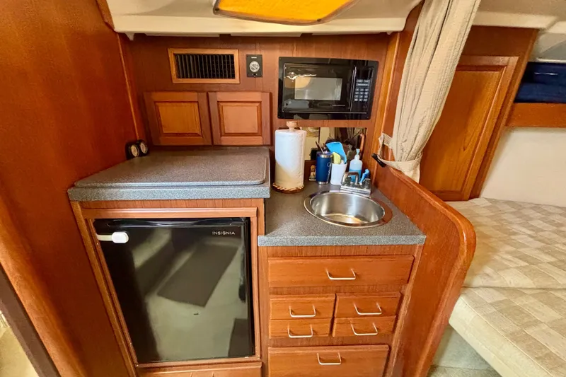 Slide: The Image of Compact kitchen area in a 2002 Luhrs 32 Open boat with sink, microwave, and mini fridge. - 46