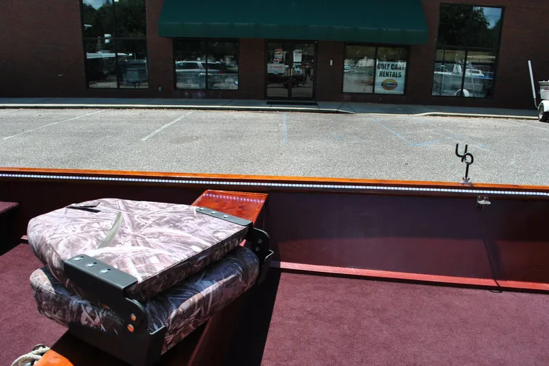 Slide: The Image of Custom 2014 Underwood boat interior with camouflage seats, parked near a rental shop. - 14