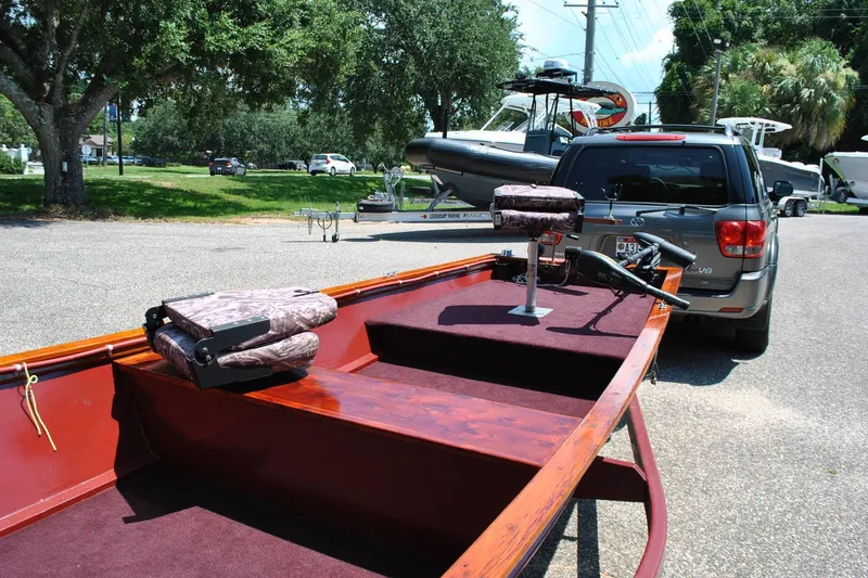 Slide: The Image of Custom Underwood 2014 boat with camo seats, parked near a vehicle in a sunny lot. - 7