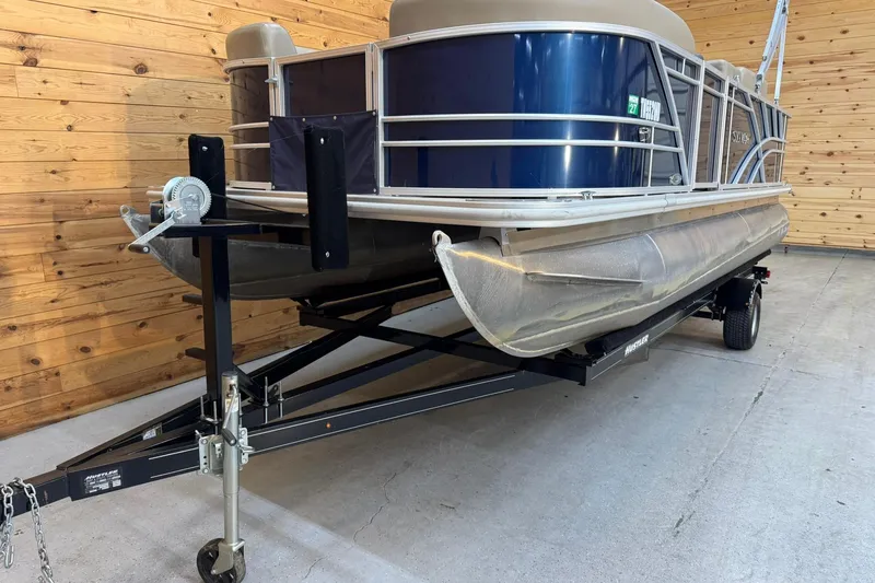 Slide: The Image of 2024 Sylvan Party Fish 820 pontoon boat on trailer in wooden garage. - 3
