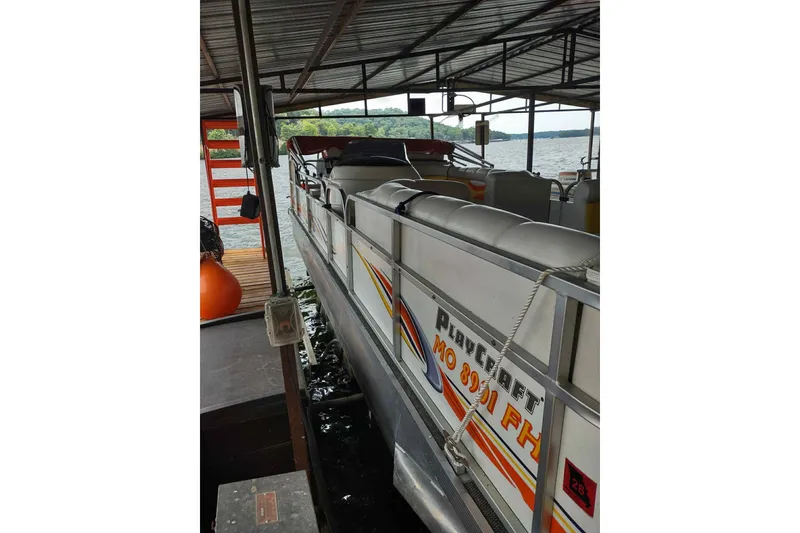 Slide: The Image of 2007 PlayCraft 22 Clipper pontoon boat docked under a covered structure. - 2