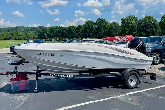 Slide: The Image of 2022 Tahoe T6 boat on trailer in parking lot, sunny day, trees in background. - 1