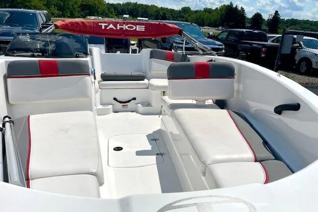 Slide: The Image of 2022 Tahoe T6 boat interior with white and red seating, parked outdoors. - 7