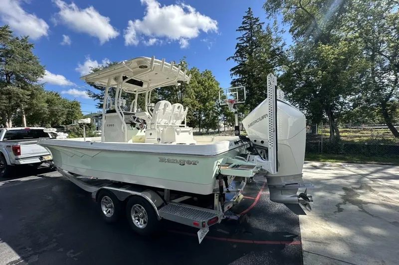 Slide: The Image of 2022 Ranger 2360 Bay boat on trailer, parked outdoors under a clear blue sky. - 13