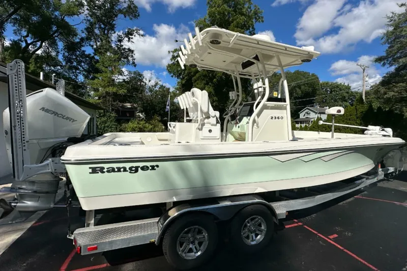 Slide: The Image of 2022 Ranger 2360 Bay boat on trailer, featuring Mercury engine, parked outdoors. - 14