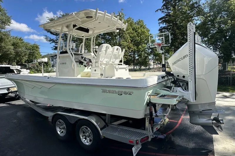 Slide: The Image of 2022 Ranger 2360 Bay boat on trailer with Mercury outboard motor, parked outdoors. - 15