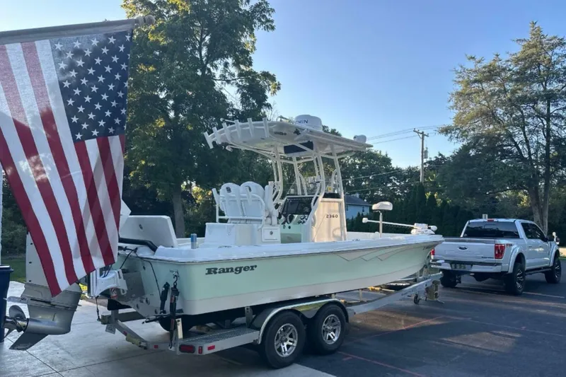 Slide: The Image of 2022 Ranger 2360 Bay boat on trailer, American flag, parked beside a truck. - 17