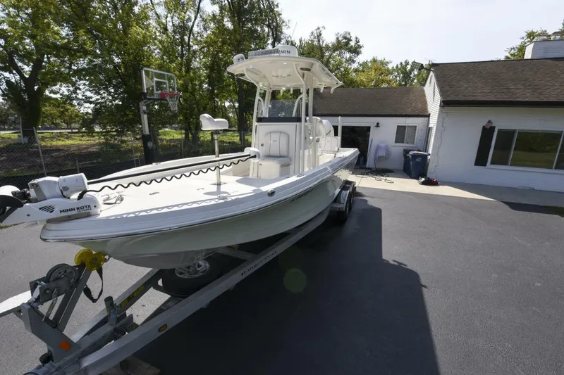Slide: The Image of 2022 Ranger 2360 Bay boat on trailer in driveway, near house and trees. - 23