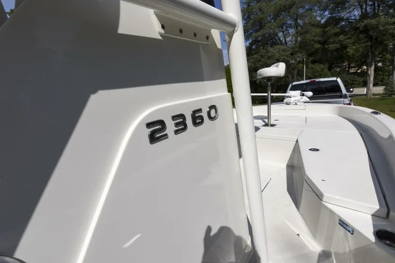 Slide: The Image of 2022 Ranger 2360 Bay boat, white exterior, parked outdoors with trees in background. - 26