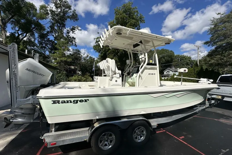 Slide: The Image of 2022 Ranger 2360 Bay boat with flags, anchored in clear water under a blue sky. - 3