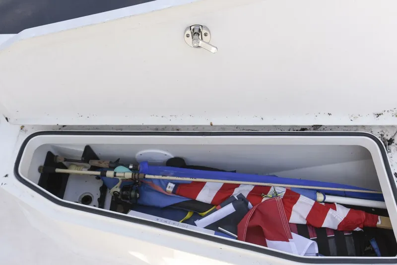 Slide: The Image of Open storage compartment on 2022 Ranger 2360 Bay boat with fishing gear and flags. - 55