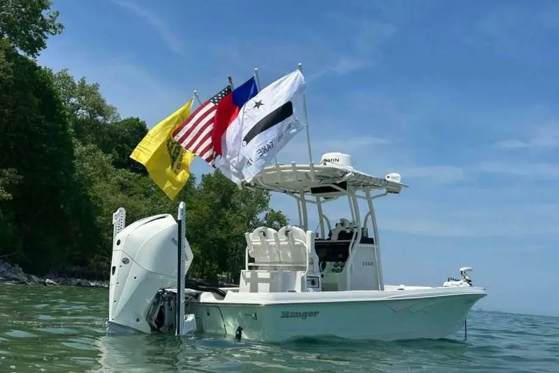 Slide: The Image of 2022 Ranger 2360 Bay boat on trailer, parked outdoors near a white building. - 7