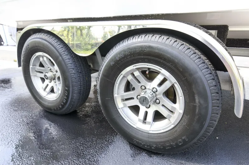 Slide: The Image of 2022 Ranger 2360 Bay trailer wheels on wet pavement, featuring durable tires and alloy rims. - 89