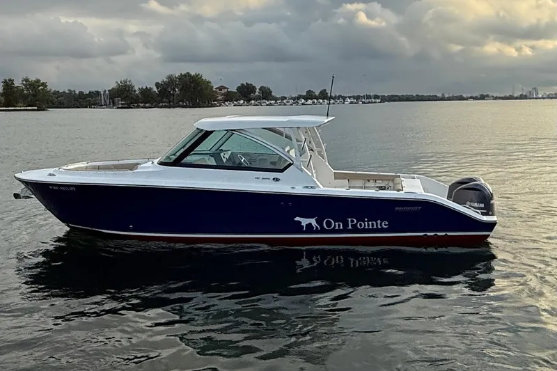 Slide: The Image of 2016 Pursuit DC 325 Dual Console boat on calm water at sunset. - 11