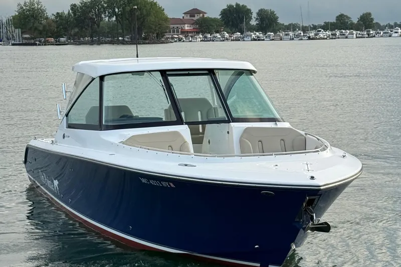 Slide: The Image of 2016 Pursuit DC 325 Dual Console boat on calm water near marina. - 14