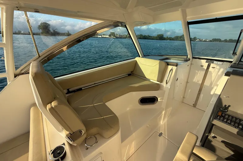 Slide: The Image of 2016 Pursuit DC 325 Dual Console interior with beige seating, overlooking calm waters. - 22