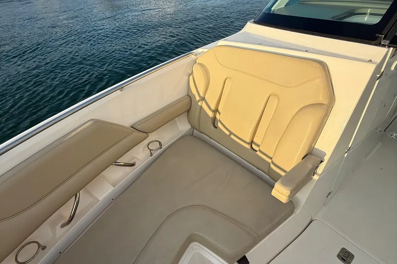Slide: The Image of 2016 Pursuit DC 325 Dual Console boat interior with beige seating by the water. - 33