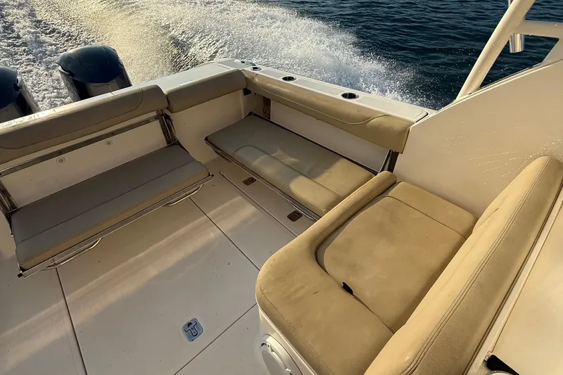 Slide: The Image of 2016 Pursuit DC 325 Dual Console boat interior with beige seating and ocean backdrop. - 40