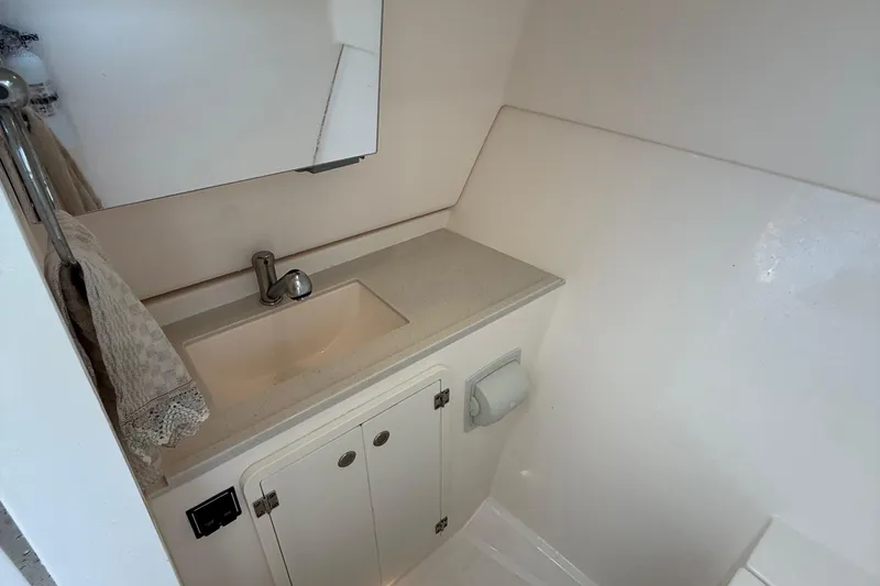 Slide: The Image of 2016 Pursuit DC 325 Dual Console boat bathroom with sink, mirror, and storage cabinet. - 45