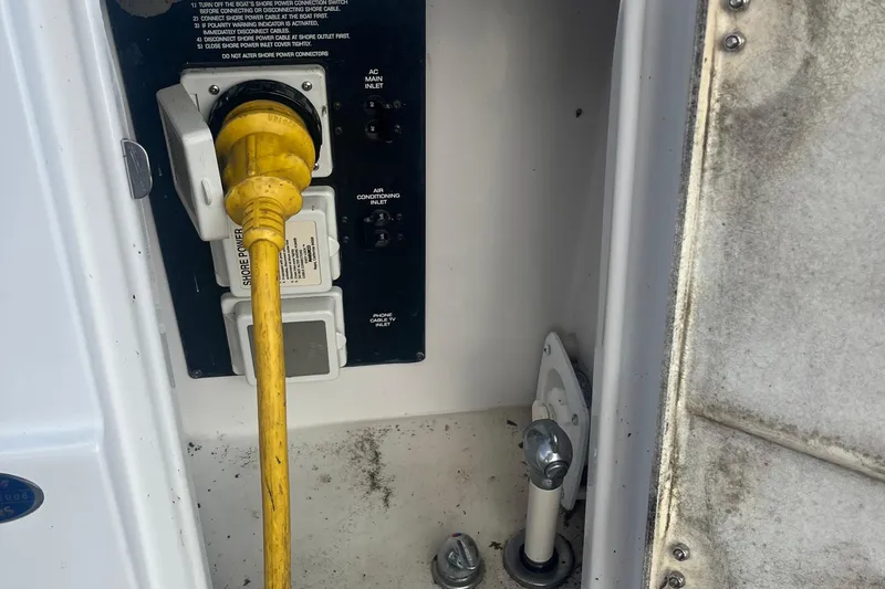 Slide: The Image of 2016 Pursuit DC 325 Dual Console shore power connection with yellow cable and control panel. - 57