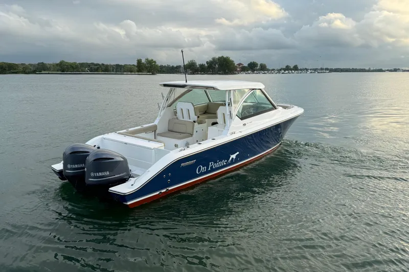 Slide: The Image of 2016 Pursuit DC 325 Dual Console boat on calm water with Yamaha engines. - 6