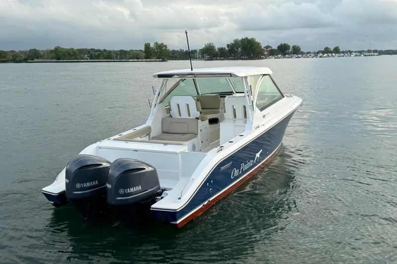 Slide: The Image of 2016 Pursuit DC 325 Dual Console boat with twin Yamaha engines on a calm lake. - 7