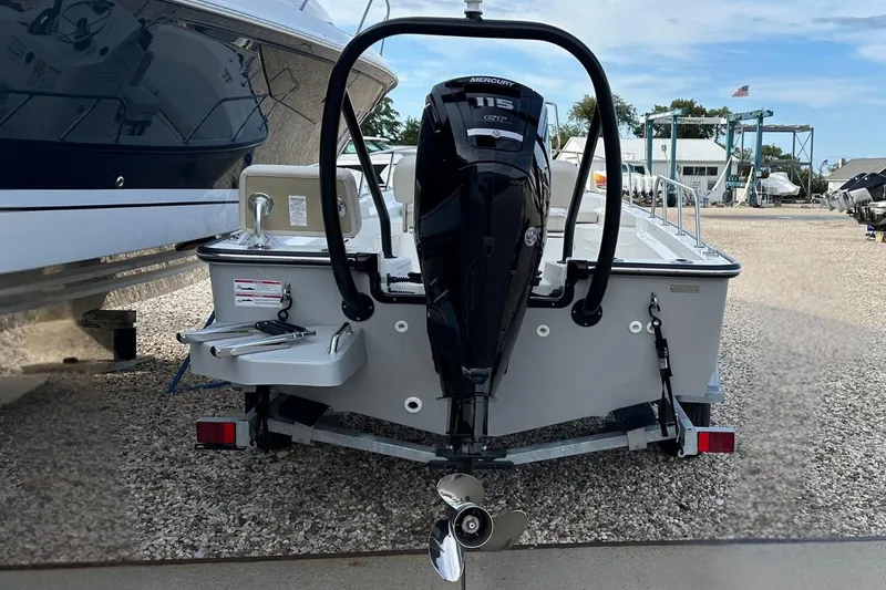 Slide: The Image of 2026 Boston Whaler 170 Montauk boat with Mercury 115 engine, parked on gravel. - 2