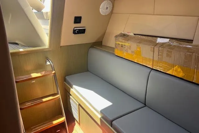 Slide: The Image of 2024 Bracewell 25 interior with gray seating, wooden steps, and a cardboard box. - 12