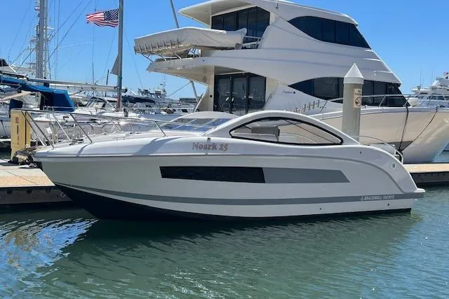 Slide: The Image of 2024 Bracewell 25 boat docked at marina, sleek design, sunny day, American flag in background. - 33