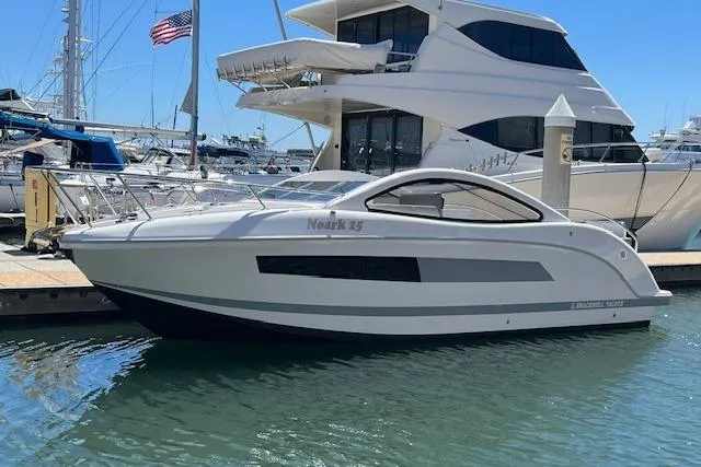 Slide: The Image of 2024 Bracewell 25 boat docked at marina, sleek design, sunny day, American flag in background. - 34